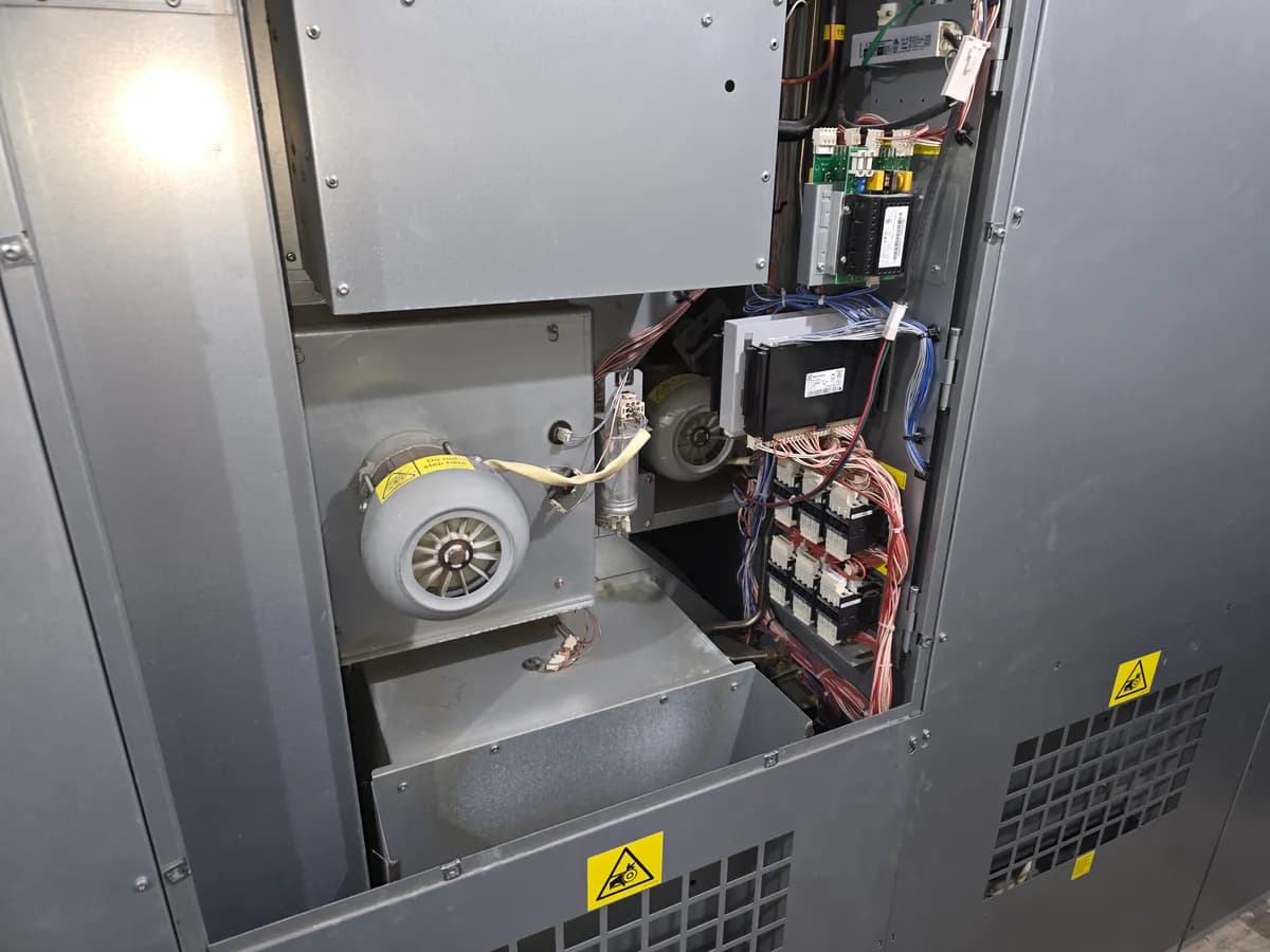 Open commercial dryer cabinet showing the blower motor and control board