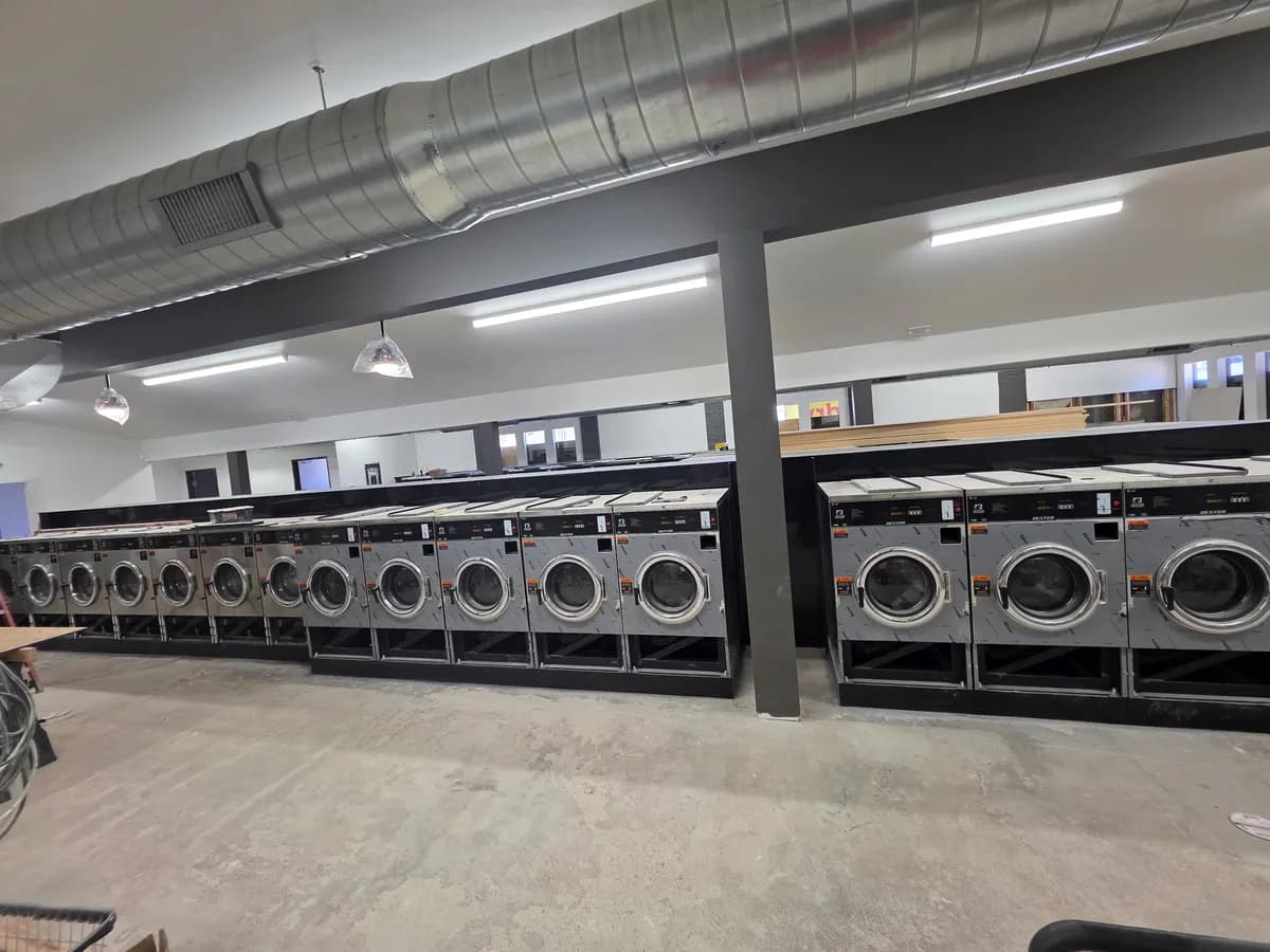 Laundromat under construction with rows of new washers being installed